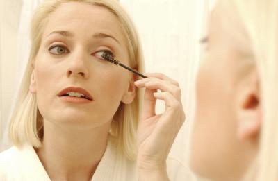 Une femme applique le maquillage des yeux dans le miroir.