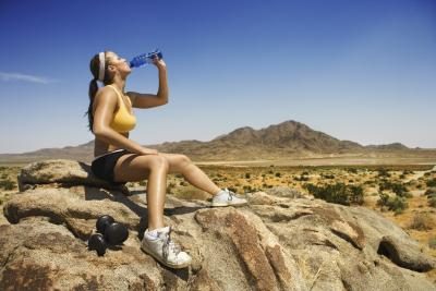 Un randonneur femme boit une bouteille d'eau sur un sentier de montagne