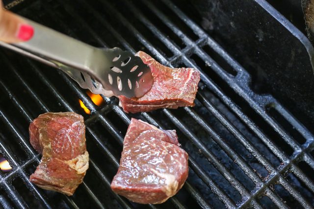Tourner le filet steak sur grill avec des pincettes.