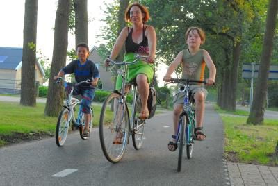 Une femme monte son vélo avec deux garçons.