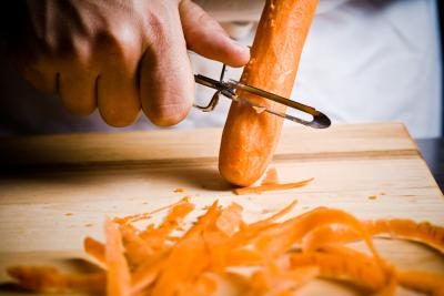 Un cuisinier épluche une carotte.