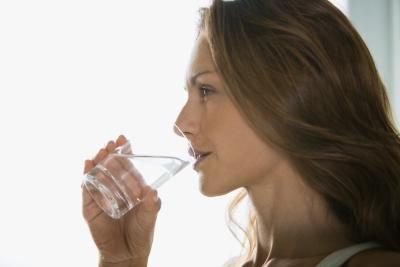 Une femme boit un verre d'eau.