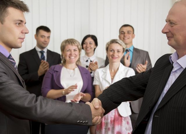 Les hommes d'affaires se serrant la main avec les employés applaudissent en arrière-plan