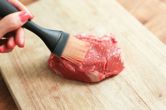Brossage huile sur un haut de surlonge steak.