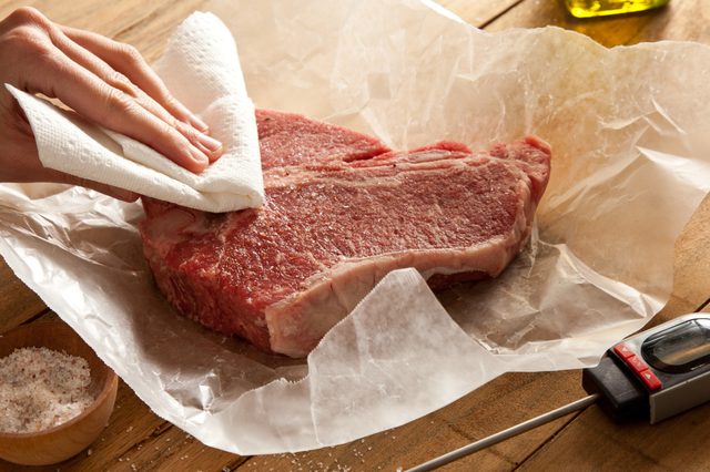 Steak cru pat vers le bas avec des serviettes en papier.